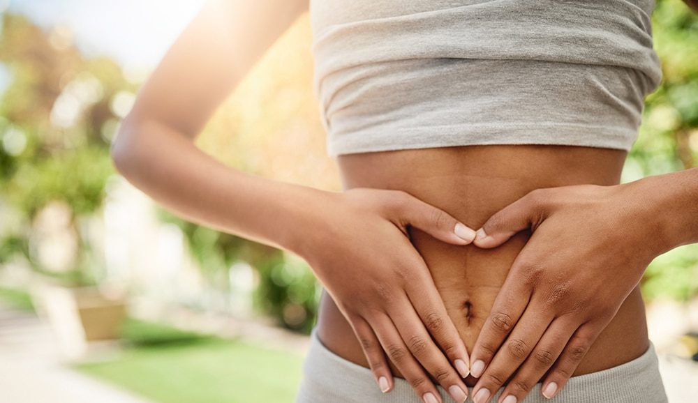 a woman with her hands placed over her abdomen in the shape of a heart