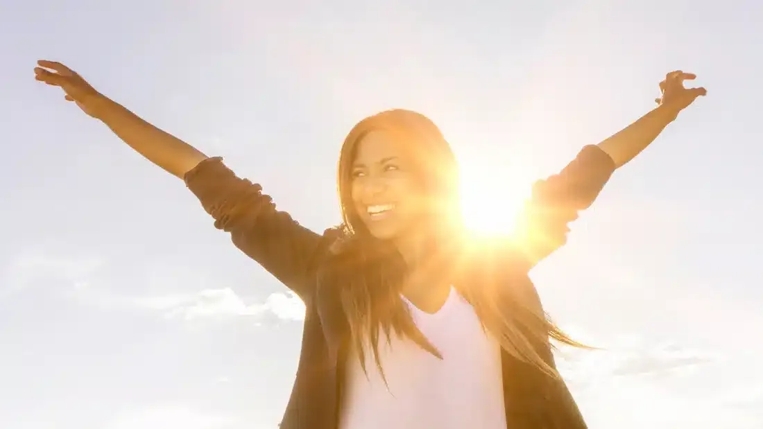 a woman smiling with the sun behind her